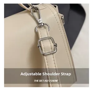 Vue détaillée de la bandoulière réglable avec boucle en métal argenté sur un sac crème