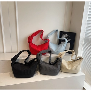 Multiple colorful quilted nylon crossbody bags displayed on minimalist white stairs