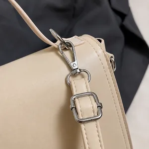Vue macro du crochet en métal argenté et boucle sur un sac en similicuir beige