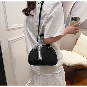 Side view of black pebble leather bowling bag with decorative organza ribbon on model