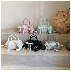 Détail de sacs à main pastel avec nœuds en dentelle et pendentifs cœur sur pierre