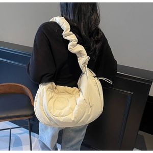 Detail view of quilted cream-white bag with stylish ruffled shoulder strap on model