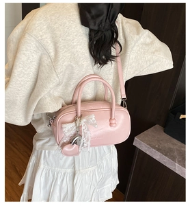 Détail du sac à main rose brillant avec nœud en dentelle et pendentif en forme de cœur