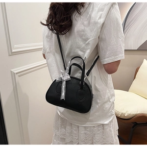 Rear view of a black pebble leather crossbody bag with a decorative logo ribbon detail