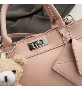 Détail de la texture similicuir rose avec fermoir rotatif argenté et charm ours en peluche
