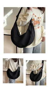 Detail of a black canvas crescent shoulder bag with wide strap and zip closure