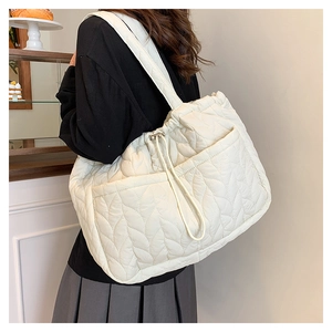 Detail view of the quilted nylon tote bag featuring leaf pattern and side pocket