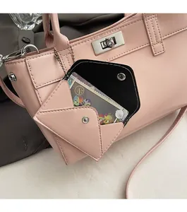Détail d'un sac à main en cuir rose clair avec une mini pochette et boucle argentée