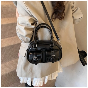 Detailed view of black shiny patent leather bowling bag with front pockets and metal buckles