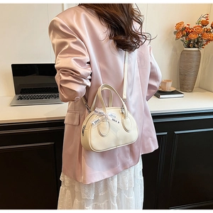 Detailed view of cream mini satchel featuring lychee grain texture and ribbon detail
