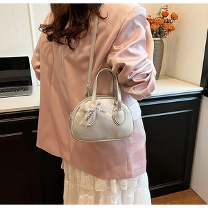 Close-up of silver mini crossbody bowling bag with a decorative Just For You ribbon bow