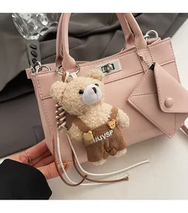 Détail d'un sac à main en cuir rose avec fermoir rotatif argenté et charm ours peluche