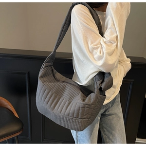 Detail of grey quilted shoulder bag with knotted strap and puffy cloud texture