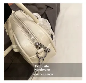 Détail du sac bowling crème avec ferrures argentées et bordures en dentelle chic