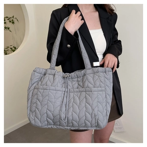 Close-up of grey quilted tote bag featuring padded leaf texture and silver buckle detail
