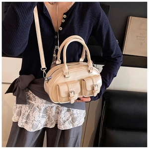 Detail of a creamy white bowling bag showing dual front flap pockets and leather texture