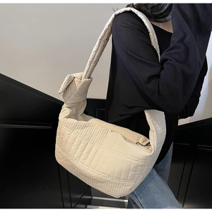 Detail showing soft quilted fabric texture and decorative knot on the beige nylon shoulder bag