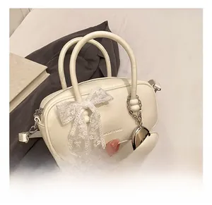 Détail du sac crème avec nœud en dentelle, breloque cœur et logo XiaoJiu