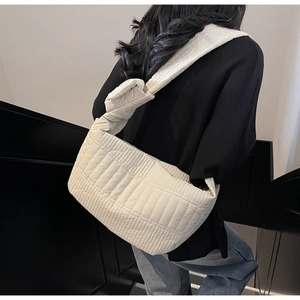 Detail of cream quilted nylon shoulder bag with knotted strap and vertical texture