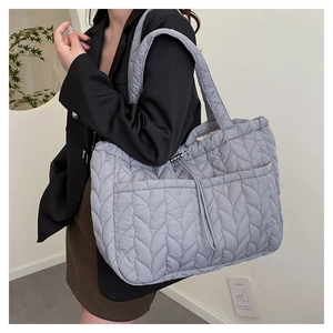 Quilted puffer tote bag side view with drawstring pockets and metallic buckle detail