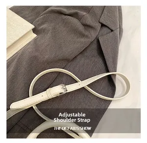 Détail d'une bandoulière réglable en cuir blanc cassé avec boucle en métal argenté