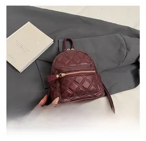 Detailansicht des weinroten Mini-Rucksacks mit Rautensteppung und goldenen Reißverschlüssen