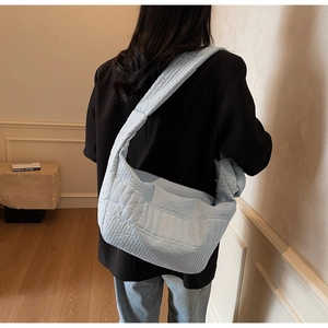 Detail of light blue quilted nylon shoulder bag showing puffy texture and spacious design