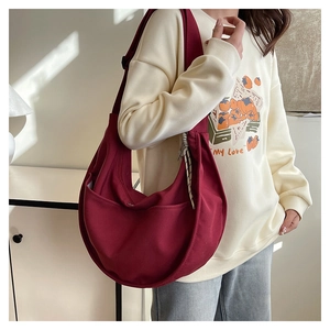Detailed macro view of deep burgundy canvas crescent bag with adjustable wide strap