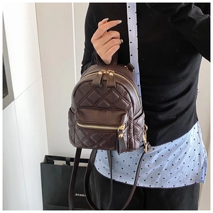 Detail eines dunkelbraunen Mini-Rucksacks mit Rautensteppung und goldenen Reißverschlüssen