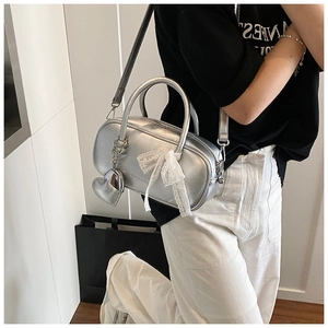 Sac bowling argenté avec nœud en dentelle blanche et breloque cœur porté en bandoulière