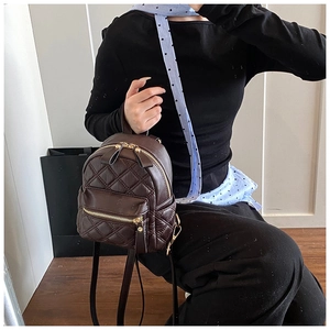 Dettaglio mini zaino in pelle trapuntata marrone scuro con cerniere in metallo dorato