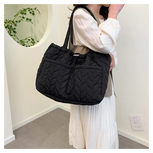 Detail of black quilted tote bag with wavy leaf pattern and silver metal drawstring