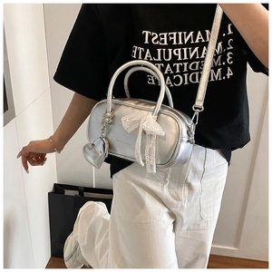 Silver metallic bowling handbag with white lace bow and heart pendant for women fashion.