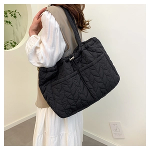 Detail of black leaf-quilted tote bag featuring drawstring closure and front pockets