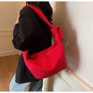 Detail view of large red quilted nylon hobo bag with knotted wide shoulder strap