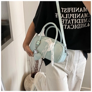 Detail of light blue glossy handbag with white lace bow and silver heart charm
