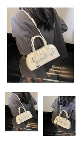 Vue détaillée du sac bandoulière crème avec pendentif cœur et bandoulière réglable