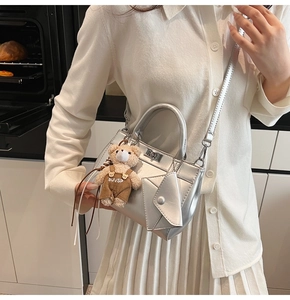 Sac à main argenté élégant avec pendentif ours et petite pochette dans un cadre chaleureux