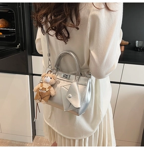 Détail du sac à main argenté métallisé avec pochette enveloppe et breloque ourson