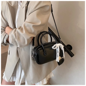 Détail du sac bowling en cuir verni noir avec nœud en dentelle blanche et cœur