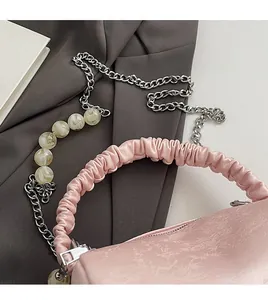 Close-up of pink crossbody bag with marble bead chain strap and ruched handle texture