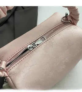 Close-up of smooth silver metal zipper on a pink pleated crossbody pillow bag