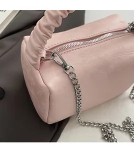 Detailed side view of pink pleated barrel bag with silver zipper and metal chain