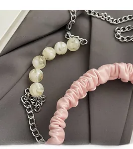 Detail of pink pleated leather handle with marble beads and silver metal chain strap