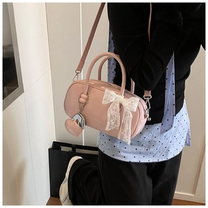 Vue détaillée du sac Boston rose avec nœud en dentelle et miroir en forme de cœur