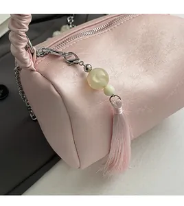 Detail of pink pleated cylinder bag with silver zipper and beaded fringe pendant