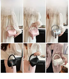 Detail of satin chain crossbody bag with pleated ring handle and long tassel charm