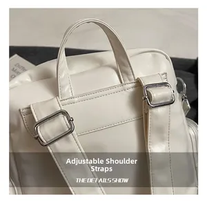 Detail showing adjustable shoulder straps and silver metal hardware on a cream PU backpack