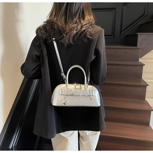 Sac bowling argenté avec pendentif coeur porté à l'épaule dans un décor d'escalier