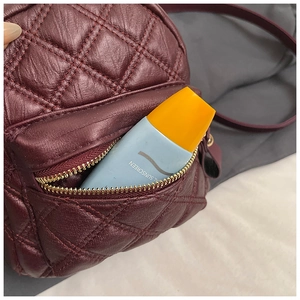 Dettaglio mini zaino trapuntato bordeaux con tasca frontale a cerniera per oggetti